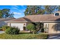 Single-story home exterior featuring a two-car garage and well-maintained landscaping at 8801 Village Green Blvd, Clermont, FL 34711
