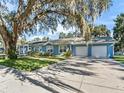 Light blue house showcasing a large oak tree, two-car garage, and manicured lawn at 1200 S 7Th St, Leesburg, FL 34748