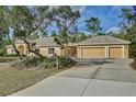 Exterior view of a house with a three-car garage and long driveway at 30629 Alder Ave, Eustis, FL 32736