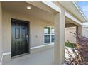 Covered front porch with black front door and white columns at 8511 Triumph Cir, Wildwood, FL 34785