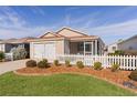 Tan house with white picket fence, two-car garage, and screened porch at 1387 Zest Ave, The Villages, FL 32163