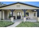 Front porch with black support beams, a rustic wood accent piece and landscaping at 17531 County Road 455, Montverde, FL 34756