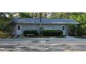 View of detached structure with gray siding, white doors, small trees and bushes surrounding at 2937 Eagles Nest Rd, Fruitland Park, FL 34731