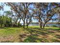 Expansive grassy backyard with mature trees providing shade, leading to a serene lake view for peaceful enjoyment at 6100 Windmill Rd, Leesburg, FL 34748