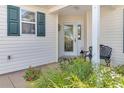 Front entrance with a glass door, black bench, and lush greenery at 906 Drakeswood Ave, The Villages, FL 32162
