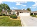 Tan single-story house with a two-car garage and manicured landscaping at 1149 Eureka Mill Run, The Villages, FL 32162