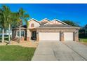 Two-story house features a three-car garage and landscaped yard at 12532 Hammock Pointe Cir, Clermont, FL 34711