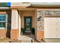 Inviting green front door entry with stonework and landscaping at 12532 Hammock Pointe Cir, Clermont, FL 34711