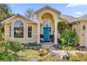 Well-maintained house with a teal door and lush landscaping at 1916 Antonia Pl, The Villages, FL 32159