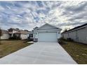 Light blue house exterior with a two-car garage and a landscaped lawn at 2046 Wallingford Loop, Mount Dora, FL 32757
