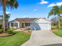 Single-story home with white siding, attached garage, and palm trees at 2338 Mcclellanville Ter, The Villages, FL 32162