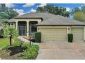 Front view of a single-story house with a three-car garage and mature landscaping at 27238 Stoney Brook Dr, Leesburg, FL 34748