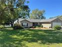 Lovely single-story home featuring a well-manicured lawn, mature trees, and a classic brick facade at 36703 Sandy Ln, Grand Island, FL 32735