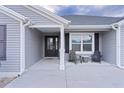 Front porch with dark gray door, two chairs, and sidelights at 11414 Roma Rd, Oxford, FL 34484