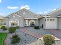 Gray house with brick walkway, landscaping, and two-car garage at 12413 Se 176Th Loop, Summerfield, FL 34491