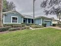 Single-story home with gray siding, a two-car garage, and a manicured lawn at 163 Crepe Myrtle Dr, Groveland, FL 34736