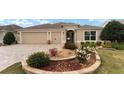 Tan house with landscaped yard, 3-car garage, and paver driveway at 2096 Odessa Cir, The Villages, FL 32162