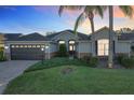 House exterior at dusk with a dark garage door and landscaping at 25220 Waterbridge Ct, Leesburg, FL 34748