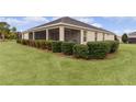 House's back elevation, showcasing a screened porch and well-manicured lawn at 3538 Mistletoe Ct, The Villages, FL 32163