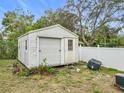 White storage shed with roll-up door in backyard at 3566 Seminole St, Gotha, FL 34734