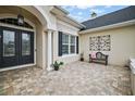 Inviting entryway with double doors, decorative wall art, and a stone patio at 4038 Swaying Palm Ct, The Villages, FL 32163