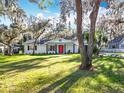 Ranch style home with a red front door and nicely landscaped yard at 405 Mission Ln, Howey In The Hills, FL 34737