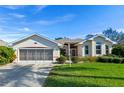 Single-story home with a two-car garage and lush green lawn at 6319 Berkshire Pass, Leesburg, FL 34748