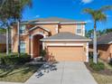 Two-story house with orange exterior, two-car garage, and landscaping at 804 Orange Cosmos Blvd, Davenport, FL 33837