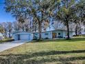 Updated mid-century modern home with light blue exterior, new garage doors, and landscaped yard at 908 N Lakeshore Blvd, Howey In The Hills, FL 34737