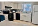 Modern kitchen featuring white cabinets, black appliances, and a tile backsplash at 13635 Berkshire Ct, Grand Island, FL 32735