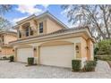 Tan two-story home with two-car garage and manicured landscaping at 14 Camino Real Blvd # 14, Howey In The Hills, FL 34737