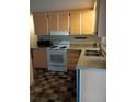 View of a bright kitchen with orange cabinets and white appliances at 164 Jacaranda Dr, Leesburg, FL 34748