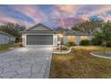 Inviting single-story home showcasing a patterned driveway, well-kept lawn, and serene sunset backdrop at 2123 Barbosa Ct, The Villages, FL 32159