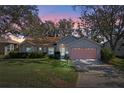 Evening view of a single-story house with a pink garage door at 25236 River Crest Dr, Leesburg, FL 34748