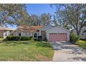 Front view of a house with a pink garage and lush green lawn at 25236 River Crest Dr, Leesburg, FL 34748