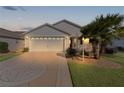 White house with a two-car garage and nicely landscaped yard at dusk at 2565 Edenville Path, The Villages, FL 32162