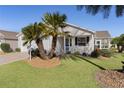 Front view of a white house with palm trees and a well-manicured lawn at 2565 Edenville Path, The Villages, FL 32162