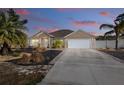 Tan house with a two-car garage, front porch, and landscaped yard at dusk at 2775 Sw 158Th St, Ocala, FL 34473