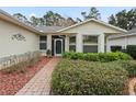 Front entry with brick walkway, lush landscaping, and decorative screen door at 353 Ranchwood Dr, Leesburg, FL 34748