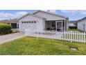 White house with a two-car garage, screened porch, and picket fence at 424 Rose Croft Ter, The Villages, FL 32162