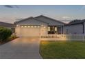 White house with a two-car garage, screened porch, and picket fence at 424 Rose Croft Ter, The Villages, FL 32162