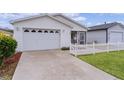 Front view of a white house with a two-car garage and a picket fence at 424 Rose Croft Ter, The Villages, FL 32162