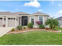 This home boasts a three-car garage, lush landscaping, and inviting entryway at 4406 Creighton Loop, The Villages, FL 32163