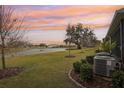 Beautiful backyard with a tranquil pond view, lush green grass, and a vibrant sunset sky at 5278 Dragonfly Dr, Wildwood, FL 34785