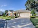 House exterior with a two-car garage and nicely landscaped front yard at 581 Society Hill Cir, The Villages, FL 32162