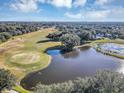 Aerial view of a golf course with a pond and houses nearby at 26748 White Plains Way, Leesburg, FL 34748