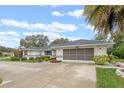 Light-colored house exterior with gray roof, two-car garage, and neatly landscaped yard at 27010 Racquet Cir, Leesburg, FL 34748