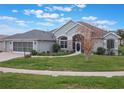 One-story house with light green exterior, two-car garage, and a landscaped yard at 27504 Stoney Brook Dr, Leesburg, FL 34748