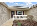 Inviting front porch with seating area, decorative door, and manicured landscaping at 507 Delfin Rd, The Villages, FL 32163