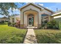 House exterior featuring a covered entryway and manicured landscaping at 5616 Illumination Ln, Leesburg, FL 34748